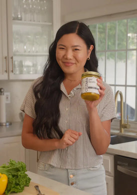 Woman holding a jar of Celtara mango gut health supplement in a kitchen.