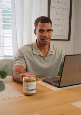 Man sitting at a desk with a laptop and a jar of Celtara mango gut health supplement.