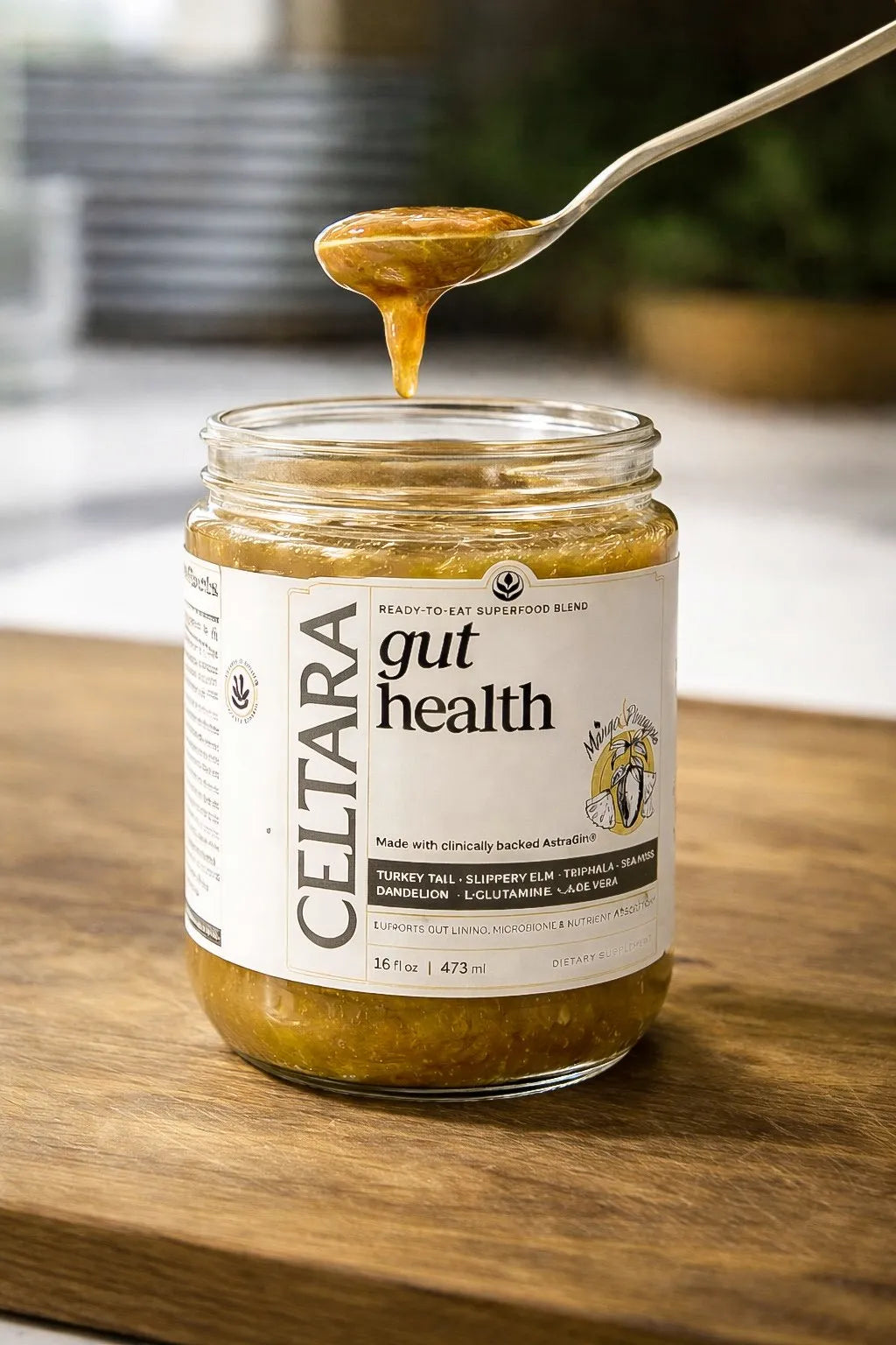 Jar of Celtara mango pineapple gut health supplement with a spoonful being lifted on a wooden surface.