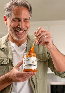 Man holding a jar of Celtara liver health supplement against a neutral background.